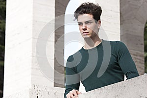 Stylish hair young man outdoors on the ledge, tight knit