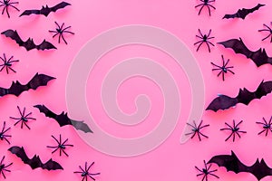 Stylish Halloween design. Bats and spiders on pink background top view space for text frame