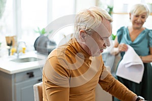 Stylish handsome attractive grey-haired bearded man sitting at the kitchen.