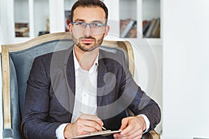 Stylish handsome calm young male sitting indoors