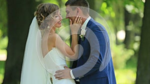 Stylish handsome groom embraces his pretty bride and kisses her in neck