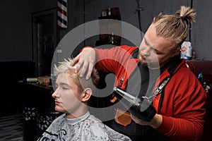 Stylish handsome man barber professional dries the hair of a guy\'s client with a hair dryer during the haircut process in a