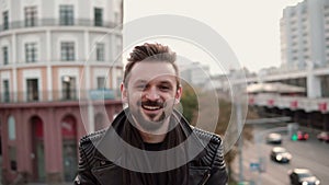 A stylish handsome man with a beard drinking takeaway coffee or tea looking to the side.