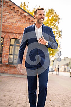 Stylish handsome man with beard, wearing elegant suit outdoor on the city street