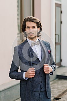 Stylish handsome man with beard, wearing suit jacket and shirt, outdoors on the city street