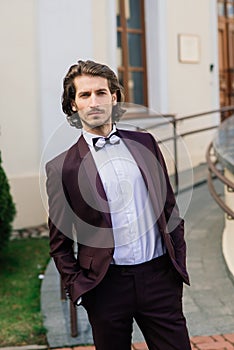 Stylish handsome man with beard, wearing suit jacket and shirt, outdoors on the city street