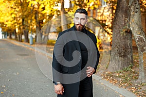 Stylish handsome man in a black coat walking outdoors