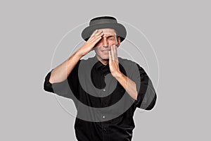 Stylish handsome man a black shirt and pork pie hat having problems isolated over grey background.