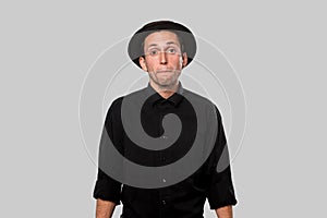 Stylish handsome man a black shirt and pork pie hat isolated over grey background