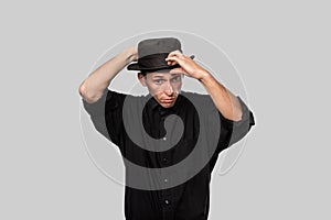 Stylish handsome man a black shirt and pork pie hat isolated over grey background
