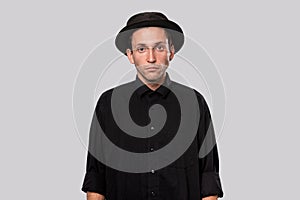 Stylish handsome man a black shirt and pork pie hat isolated over grey background