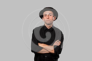 Stylish handsome man a black shirt and pork pie hat over grey background