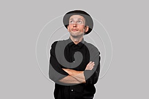 Stylish handsome man a black shirt and pork pie hat over grey background