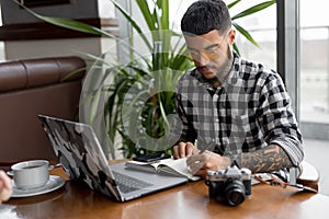 Stylish handsome man photographer freelancer working by laptop computer in cafe