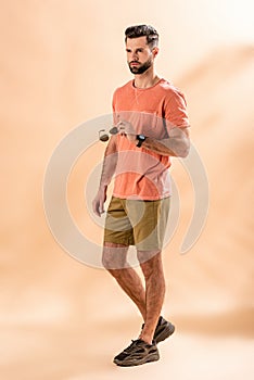 Stylish handsome man posing in shorts and summer t-shirt holding sunglasses