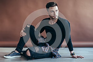 Stylish handsome man posing sitting on floor