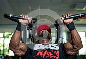 Stylish handsome muscular man training hard in gym. Strong athlete bodybuilder doing heavy exercise.