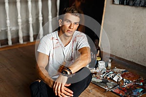 Stylish handsome young man artist in a white tank top with paint