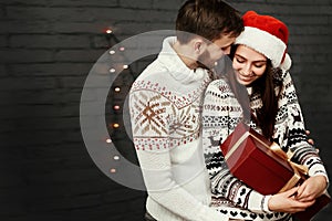 Stylish happy couple with big red present smiling gently hugging