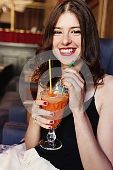 Stylish happy woman holding delicious carrot fresh smoothie and