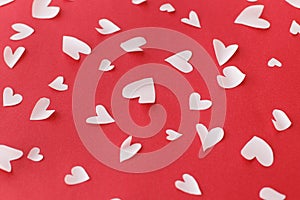 Stylish hearts composition on red background. Valentines day card. Cute little white hearts cut outs on red paper. Happy Valentine