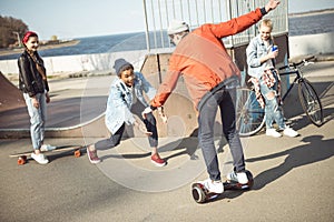 Stylish hipster boy riding gyroboard with friends near by