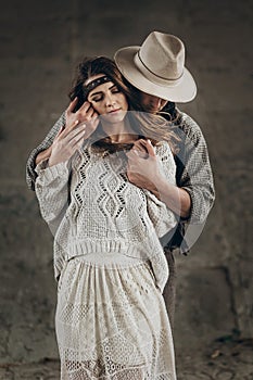 stylish hipster couple gently hugging. man in hat sensual touching boho woman in knitted sweater. atmospheric sensual moment.