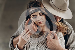 stylish hipster couple gently hugging. man in hat sensual touching boho woman in knitted sweater. atmospheric sensual moment.