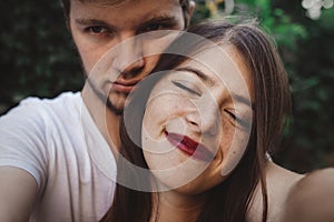 Stylish hipster couple making selfie and embracing. Happy family couple in love making self portrait and smiling in evening summer