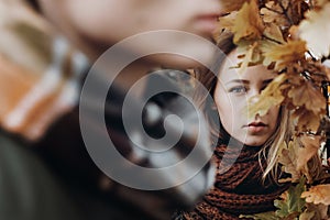 Stylish hipster couple posing and looking under yellow leaves in