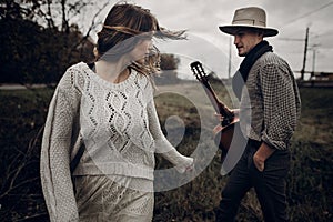 Stylish hipster couple posing. man in hat with guitar and his bo