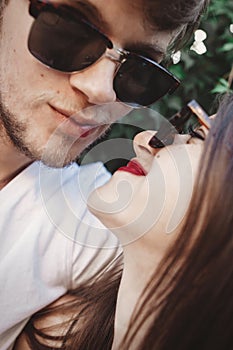 Stylish hipster couple in sunglasses smiling and making cool selfie. Happy family couple in love making self portrait and kissing