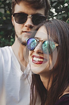 Stylish hipster couple in sunglasses smiling and making cool selfie. Happy family couple in love making self portrait and laughing
