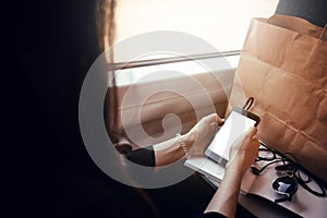 stylish hipster girl holding phone with headphones at window light in train. travelling by train concept. beautiful young woman l