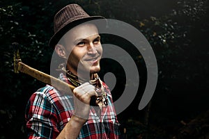 stylish hipster lumberjack with ax in the sunny forest in mountains