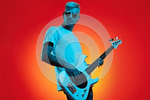 Stylish hipster man play white bass guitar in neon lights. Rock music concept.