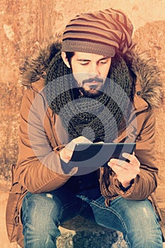 Stylish hipster man sitting using tablet with a warm tone filter