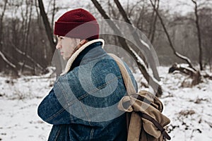 Stylish hipster traveler with backpack in red hat walking in wi