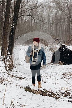 Stylish hipster traveler with backpack in red hat walking in wi