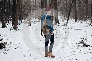 Stylish hipster traveler with backpack in red hat walking in wi