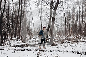 Stylish hipster traveler with backpack in red hat walking in wi