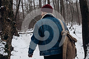 Stylish hipster traveler with backpack in red hat walking in wi