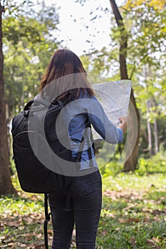 Stylish hipster traveler exploring map at sunny forest and lake in the mountains landscape