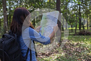 Stylish hipster traveler exploring map at sunny forest and lake in the mountains landscape