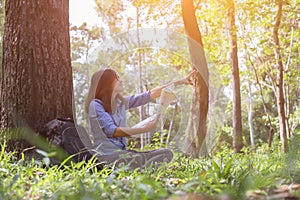 Stylish hipster traveler exploring map at sunny forest and lake in the mountains landscape