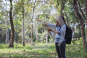 Stylish hipster traveler exploring map at sunny forest and lake in the mountains landscape