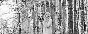 stylish hipster traveler. woman holding photo camera. taking picture in winter forest. Photographer photographing on