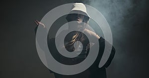 Stylish hipster woman dancing in hip hop style on smoke background