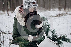 Stylish hipster woman gathering and holding pine green branches