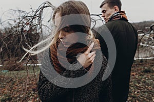 stylish hipster woman and man posing in windy autumn park. sensual atmospheric moment with space for text. fashionable cool